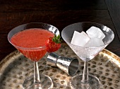 Two martini glasses with fruit martini and ice cubes
