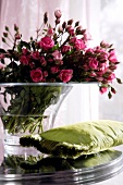Rose bouquet in glass vase and green cushion by side
