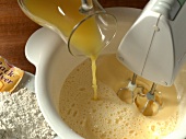 Mixing eggs while juice being poured in bowl, step 2