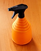Orange water sprayer on wooden background