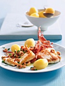 Fried plaice fillet with pancetta on plate