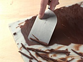 Close-up of hand making chocolate curls for cake