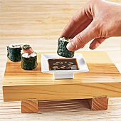 Sushi - 3 Maki Röllchen auf Holz tablett und Schälchen mit Sojasoße
