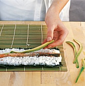 Sushi - Lachs- und Avocadostreif en werden auf Reis gelegt