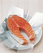 Fillet of raw fish with skin on plate with transparent foil