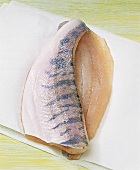 Deboned raw fish with skin on white baking paper