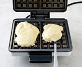 Two blobs of dough on iron machine for preparation of waffles