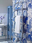 Bathroom with sink, blue cabinet and towel hanger against Asian style silver wallpaper