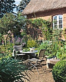2 Stühle am Tisch im grünen Garten, Bauernhaus im Hintergrund