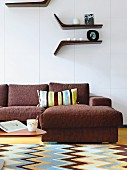 Wohnzimmerausschnitt - braune Sofakombination mit gestreiftem Kissen, davor Teppich mit gezacktem Muster im Retro-Stil