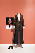 Knitted jacket and black pants styled by Paul Smith on clothes stand with photo of model