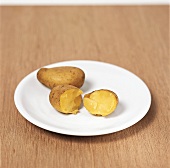 50 Kartoffelrezepte - 2 Kartof- feln mit Schale auf weißem Teller