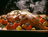 Roast leg of lamb with herb, shallots and tomatoes in baking dish