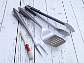 Spatula, brush, fork and tongs on wooden background for grilling