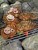 Pepper steaks with rosemary and lumberjack steak with onion on barbecue grill
