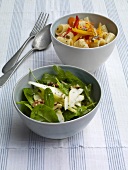 Two bowls of noodles with pepper salad and spinach with rocket salad