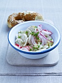 Radish and white sausage salad with onions, chives and pretzels in bowl