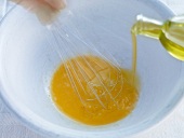 Olive oil being poured in egg yolk for preparation of cauliflower salad, step 3