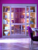 Schrank mit Glasschiebetüren, Eiche, pinke Wand und Stuhl, beleuchtet