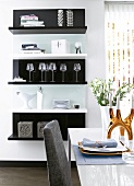 View of black and white painted shelves and set dining table with decoration