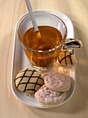 Tea in glass and macaroons with chocolate drizzle on tray