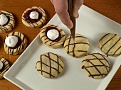 Close-up of chocolate lines being put on cookies