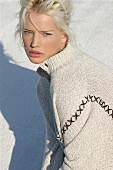 Blonde woman in a light sweater looks thoughtfully at the camera
