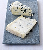 Two piece of gorgonzola cheese on chopping board