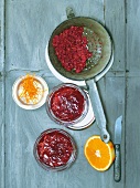 Currant and orange jelly in sieve with halved orange and orange zest