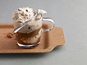 Glass of iced coffee with nuts and cream on tray