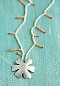 Close-up of necklace made of coral beads with silver flower pendant