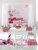 Children room in pink and white with floral pattern table, chairs, pillows and blanket