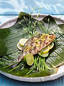 Grilled seabream on banana leaves with lemon slices and lime wedges
