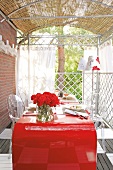 Balkon mit imposantem roten Tisch und transparenten Stühlen