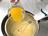 Melted butter being poured and whisked in bowl for preparation of bearnaise sauce, step 3