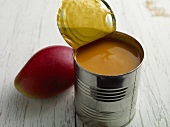 Mango puree in steel jar with fresh mango on side