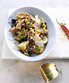 Pasta salad with olives, artichokes and salami in serving dish