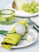 Mit Rosen dekorierte grüne Serviette auf einem weißen Teller