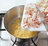 Lobster and vegetables being heated in saucepan for preparation of lobster ravioli, step 1