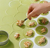 Dough circles being filled with lobster filling for preparation of lobster ravioli, step 2