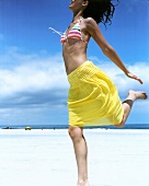 Cheerful woman in yellow skirt enjoying on beach and laughing heartily