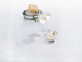 Cheese and two glasses of white wine on white background