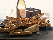 Cheese sticks with caraway, bottle of white wine and glass