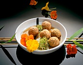 Chicken balls with nasturtium flowers in bowl