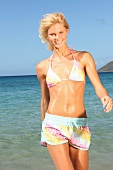 Frau blond am Strand, Blick in Kamera im Bikini und Shorts