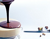 Melted chocolate being poured on cake with nuts and cake knife, copy space