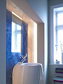 Bathroom with deep large sink against blue recessed wall mirror