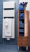 Brown bathroom cabinet with blue towels and wall heater