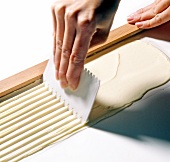 Close-up of hand pulling comb on white chocolate, step 1