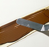 Close-up of dark chocolate being smoothened on white chocolate, step 3